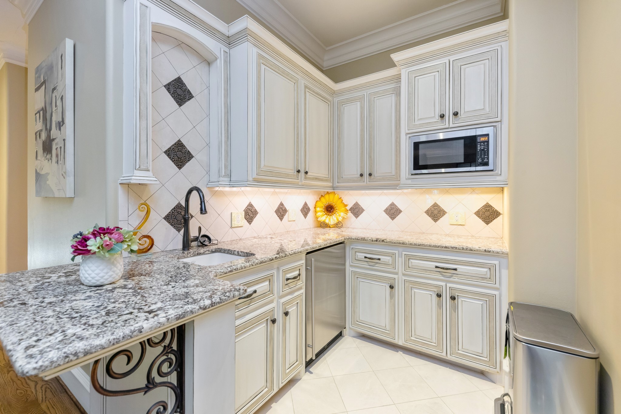 Kitchenette has granite countertops, mini fridge, sink, and microwave as well as custom cabinetry.