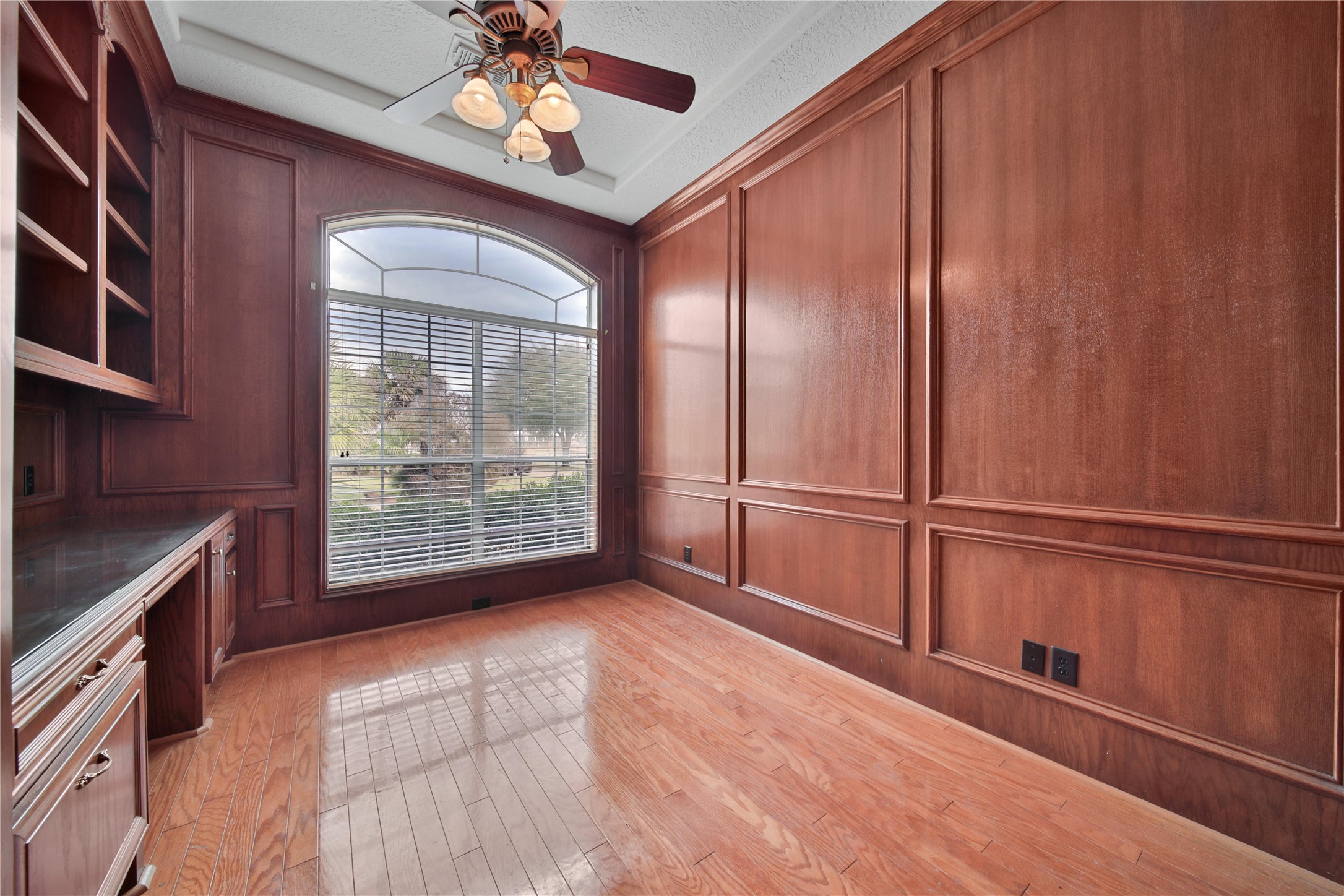Study with double french glass doors, built in desk and wood paneling.
