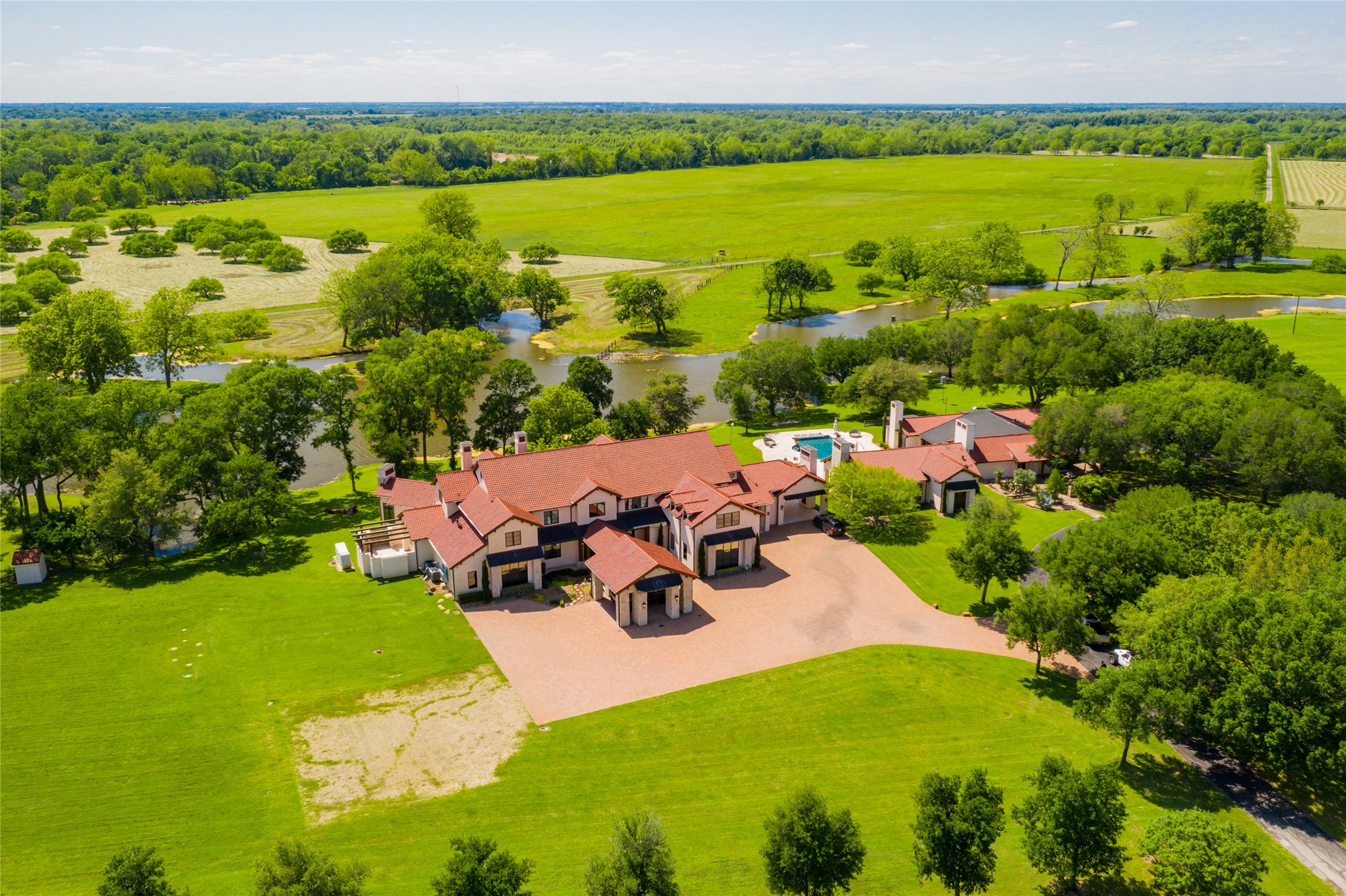 The incomparable Board Oaks Ranch in Hempstead, includes 1,408+/- acres of 3.5 miles of Brazos River frontage with beaches, ponds, 8+ acre stocked fishing lake, 5 water wells, improved/extensive open pastures and thick woods providing natural habitat for wildlife. Aerial view shows exquisitely appointed 4 bedroom/5 full bath/6 half baths main house, pool/hot tub/water features, remodeled 3 bedroom/3 bath guesthouse, barndominium, 8 stall horse barn and so much more!