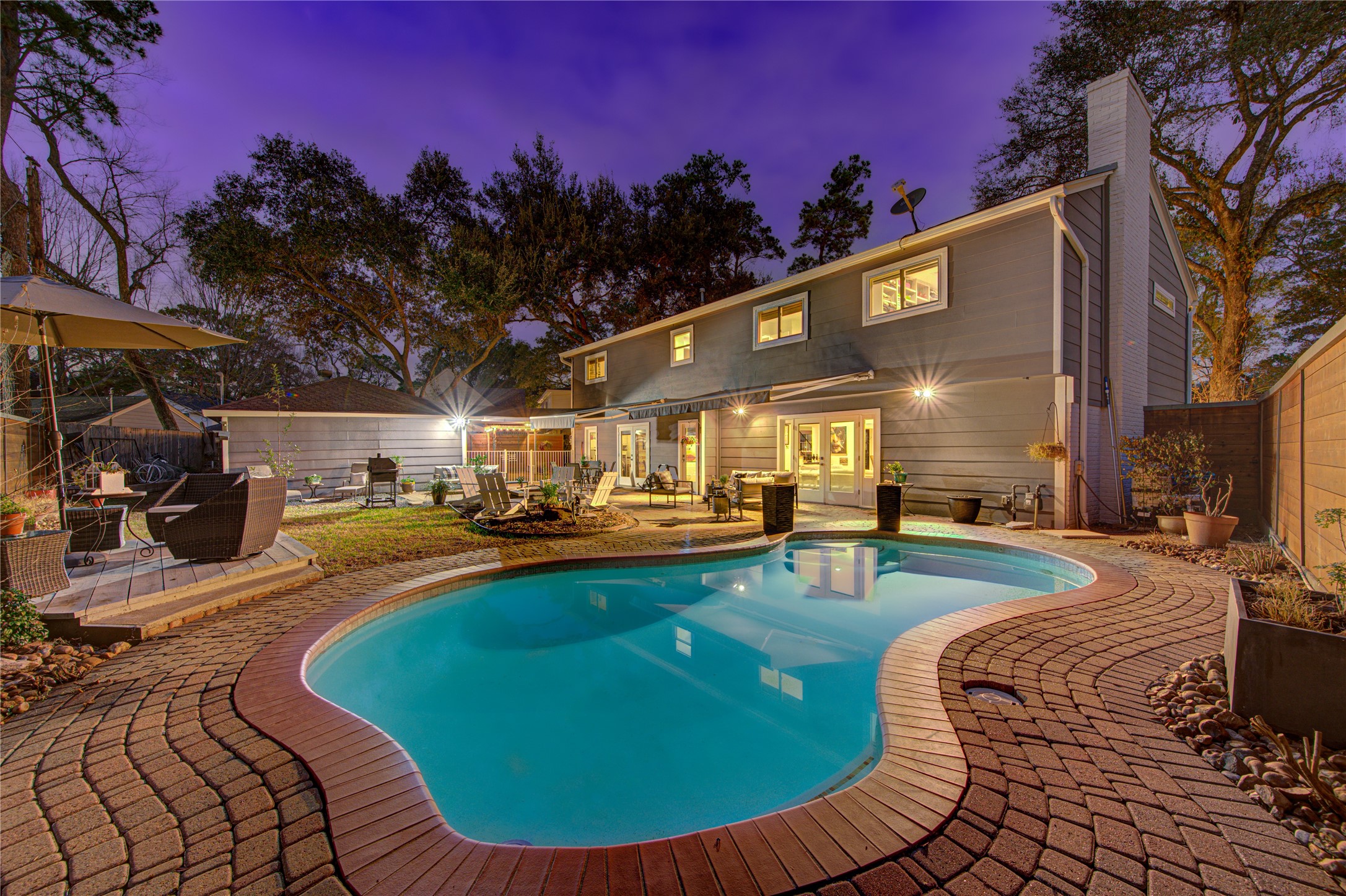 Dusk view of the backyard highlighting the sparking pool with brick pavers. So much space to play and entertain outdoors.