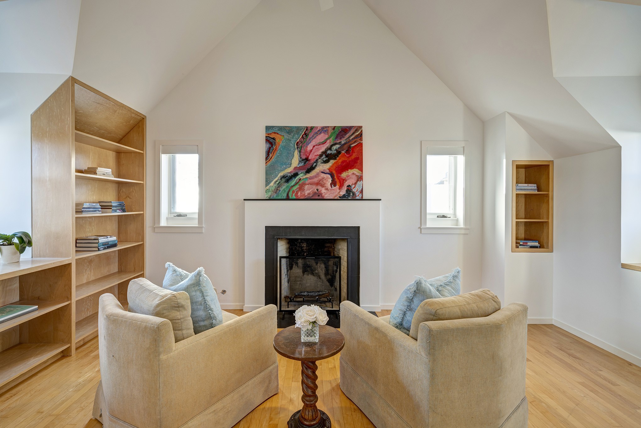 Sitting room of the primary bedroom with fireplace, built-ins and vaulted ceiling.