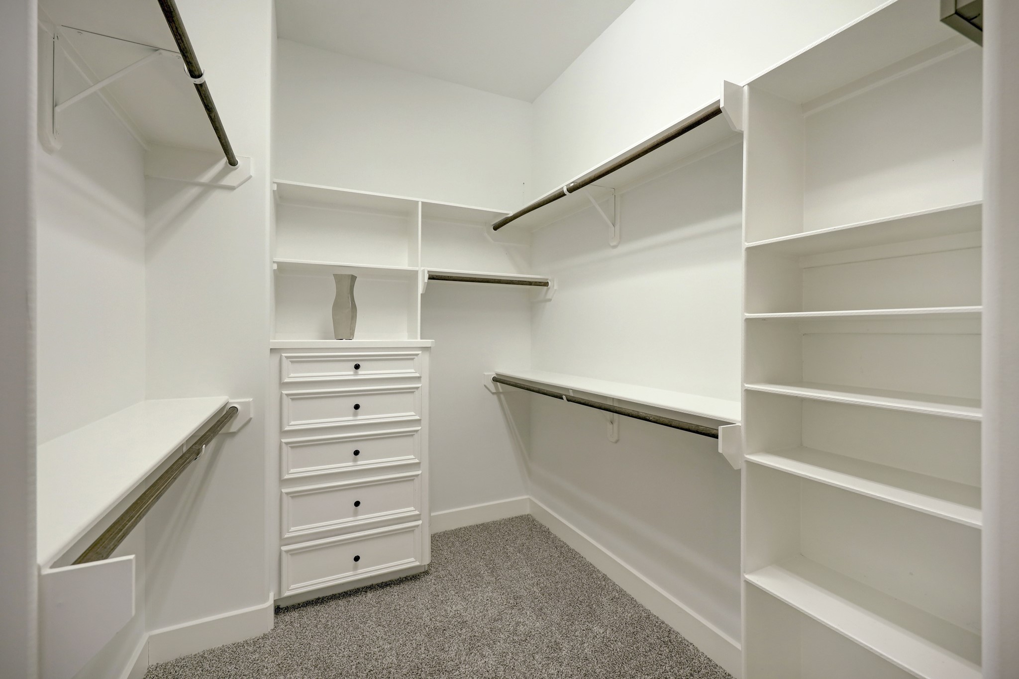The primary suite also includes a spacious walk-in closet with hanging rods, built-in shelves, and an integrated chest of drawers.