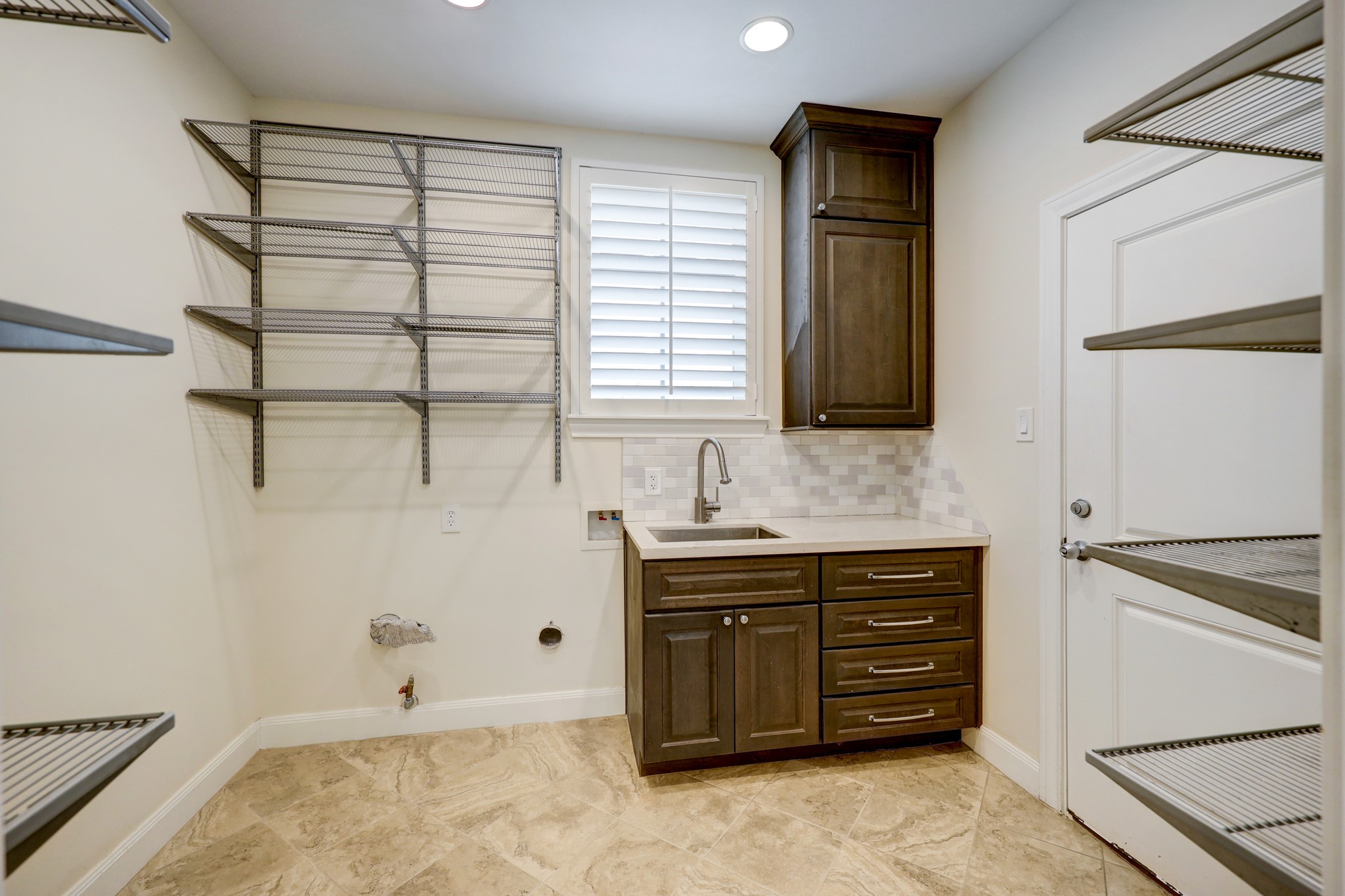 Utility room just off of the kitchen features custom Elfa shelving for plenty of storage, utility sink area, and 2