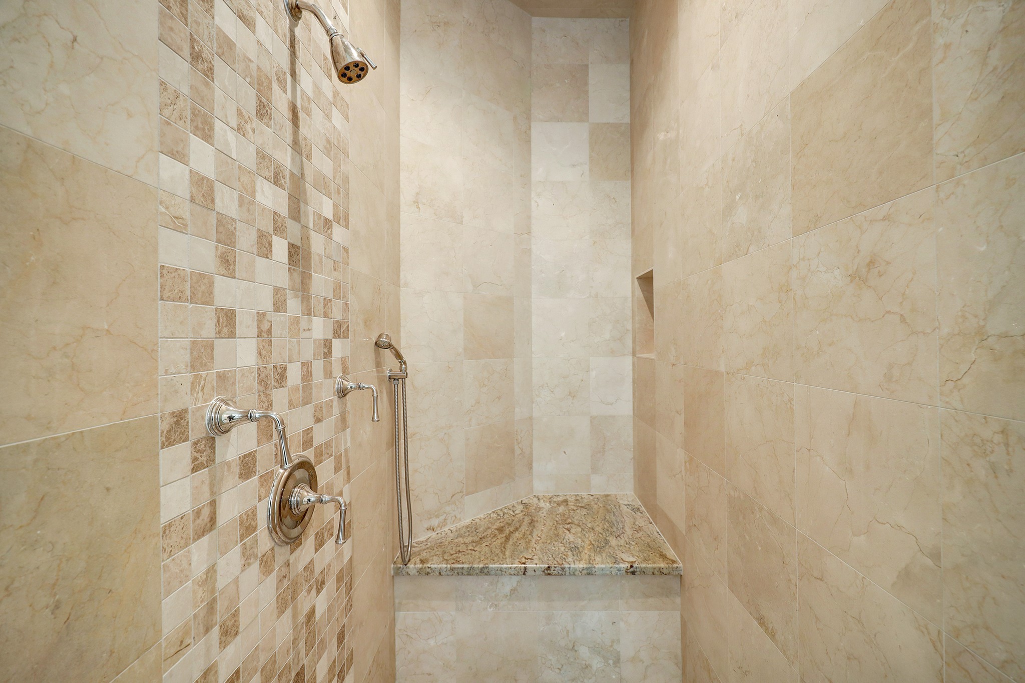 LARGE SHOWER WITH EXTRA ARM SPRAYER AND SEAT MADE OF MARBLE AND TRAVERTINE.  BEAUTIFUL NEUTRAL TONES.