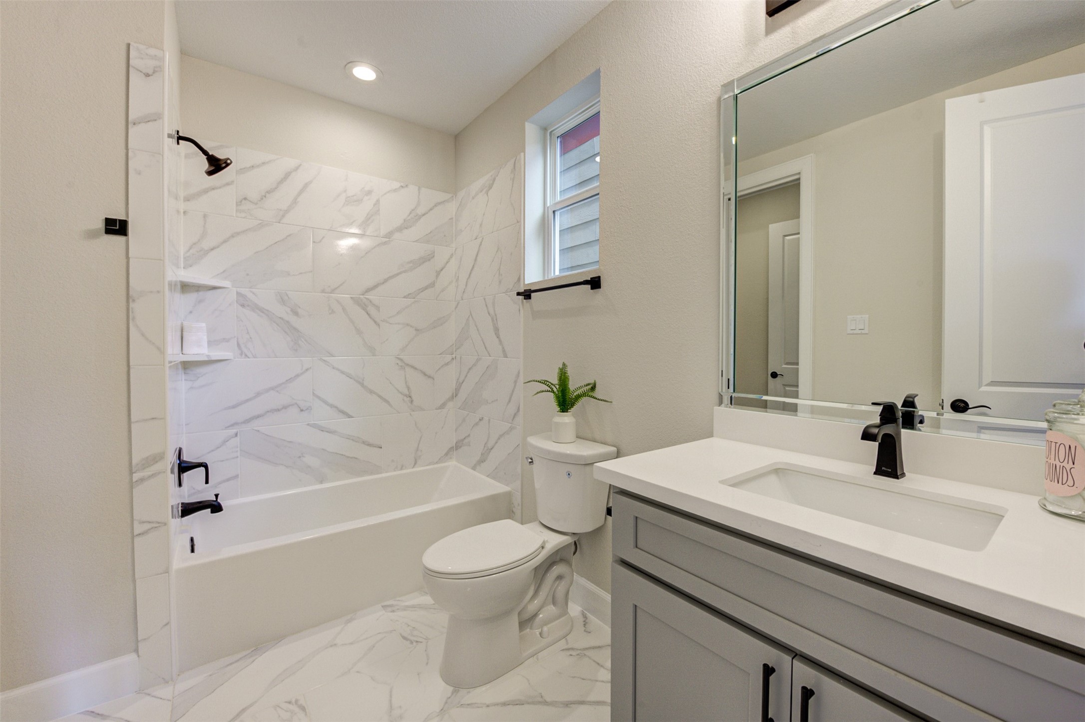 Lovely full bathroom on the first floor with quartz countertop and black hardware.