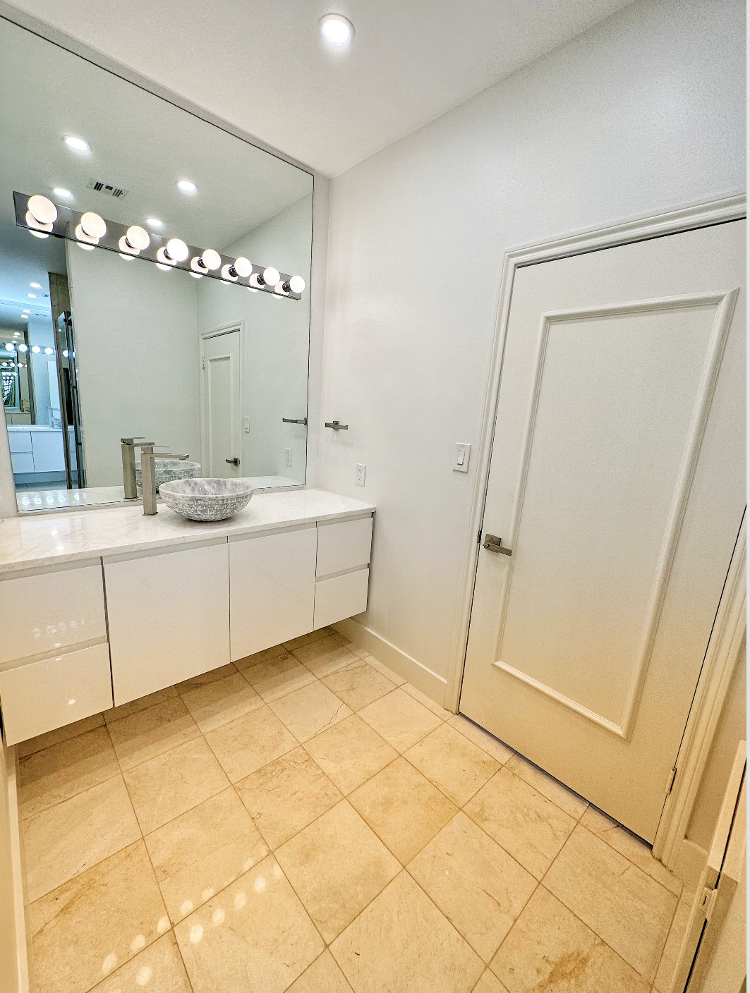 2 of 2 primary bathroom vanities with marble counters and marble flooring