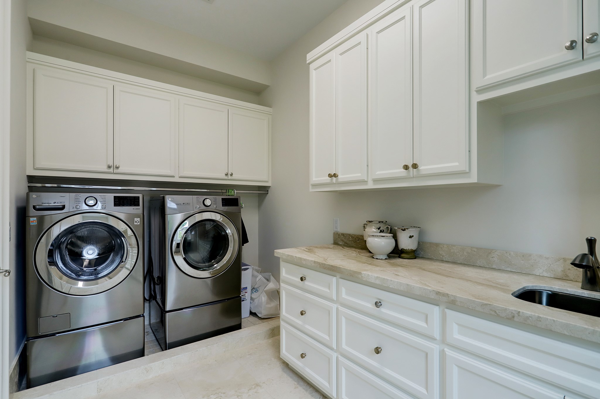 Utility room with sink and wonderful cabinet and counter space. High-end washer & dryer convey with the home.