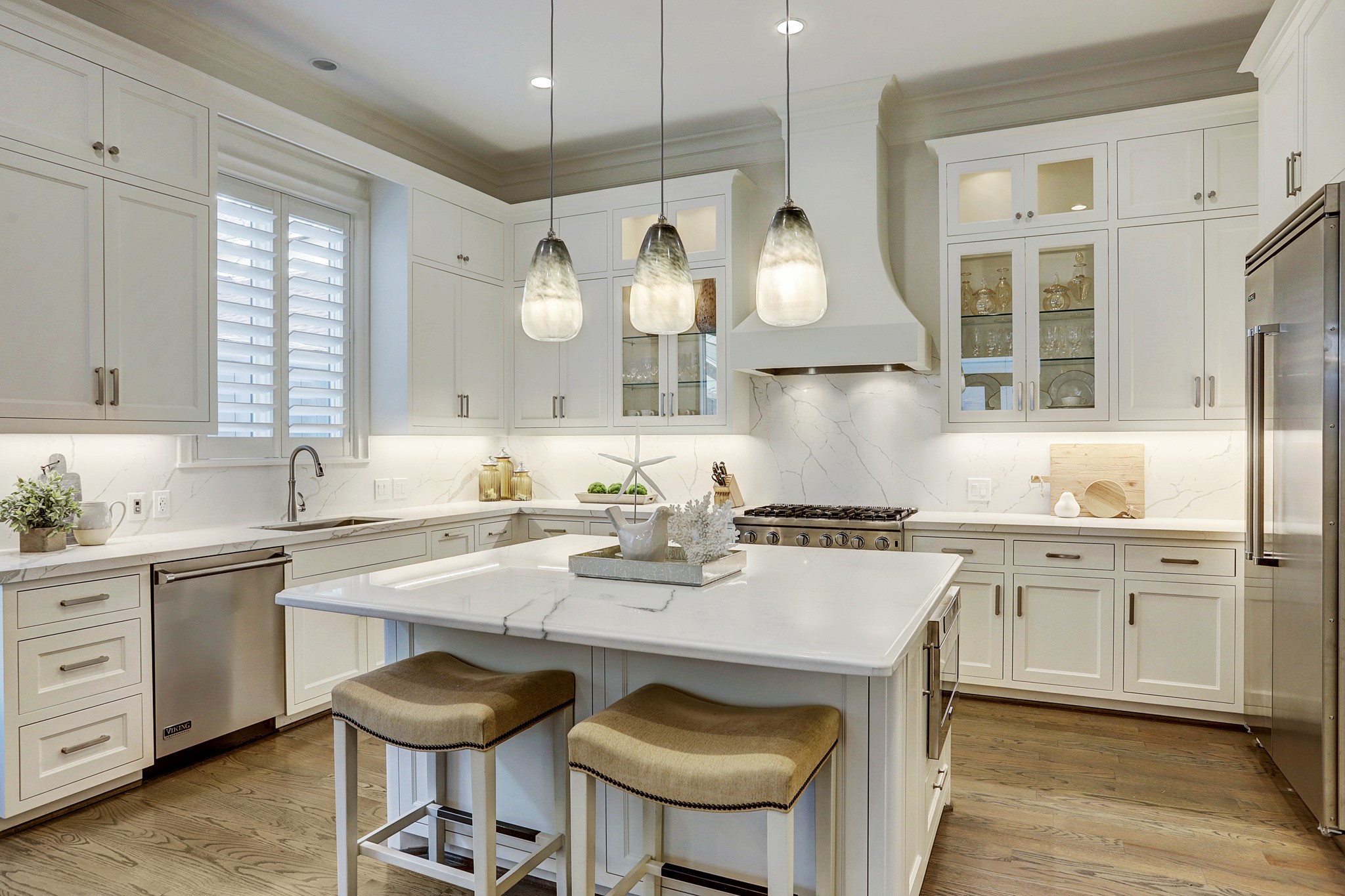 The gourmet kitchen has a marble island with knee space for additional seating and storage below; Viking appliances; glass front cabinets; upgrades include new quartz counter tops for the remaining counters, new stainless sink with Insinkerator disposal and new designer pendant lighting.