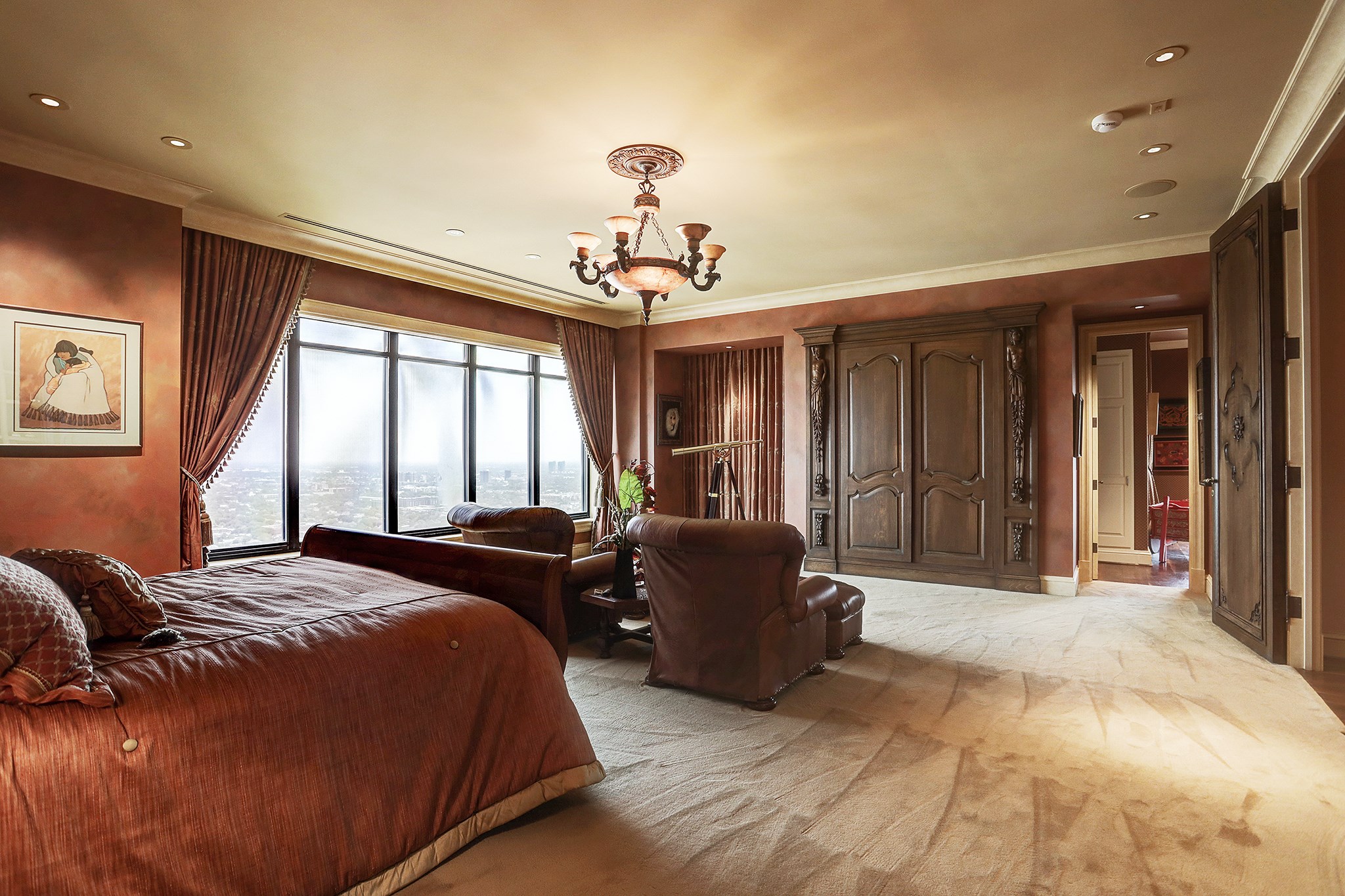 The Primary Bedroom with sitting area has faux Venetian plaster walls, access to the second balcony, entertainment center behind the oversized carved cabinet doors and outstanding views.