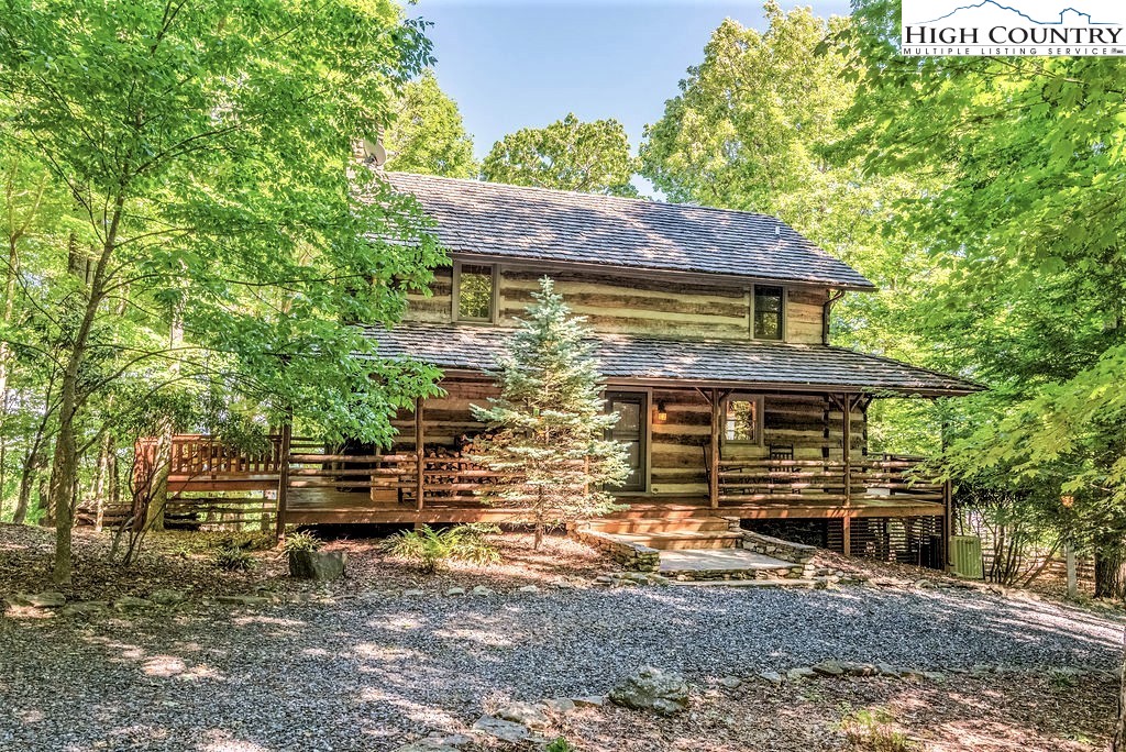 This antique log cabin in Stonebridge has a charming rustic elegance, unique features throughout, and desirable long range layered views!!! Main level offers an open concept for easy flow when entertaining and a sense of being together when just hanging around the home. Great room offers a native stone wood-burning fireplace, custom designed kitchen upgraded with stainless appliances, including gas range, beautiful granite countertops, center island and walk-in pantry. Dining area can easily accommodate large family feasts. Leave the hectic pace of city life relaxing on the covered wrap-around deck with stunning sunrise views and majestic mountain vistas. The hand hewn staircase and the unique catwalk with built-in bookcases leads you to the open
loft with large master suite. The lower level offers a private guest bedroom and full bath along with a
spacious family room with second wood-burning fireplace and can easily be set up with an additional sleeping
area. The lower level opens out to a tiled patio and a fenced backyard equipped with a fire pit, ideal for children and pets or a garden space. Circular driveway for easy access. Cabin being sold mainly furnished.