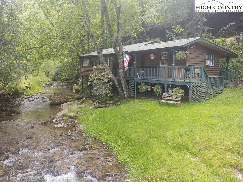 STUDENT RENTAL/LONG TERM RENTAL/VACATION RENTAL! Located a mere two miles from Boone, this mountain cottage sits on beautiful Goshen Creek. The roof and siding were updated in 2013. Home was remodeled with new carpet in bunkhouse.  Flooring updated and painted. Heating upgraded to propane monitor in both buildings and window A/C units keep cool in summer. Sit and swing on the shaded, covered deck and watch the creek flow by. Access the adjacent bunkhouse only a few steps across the covered deck. As an added convenience, the bunkhouse has its own full bathroom. The bunkhouse adds an additional 223 square feet and enclosed porch adds another 134 square feet of usable space. No restrictions on rentals makes this property even more versatile. New kitchen countertop, sold partially furnished, exclusion list included