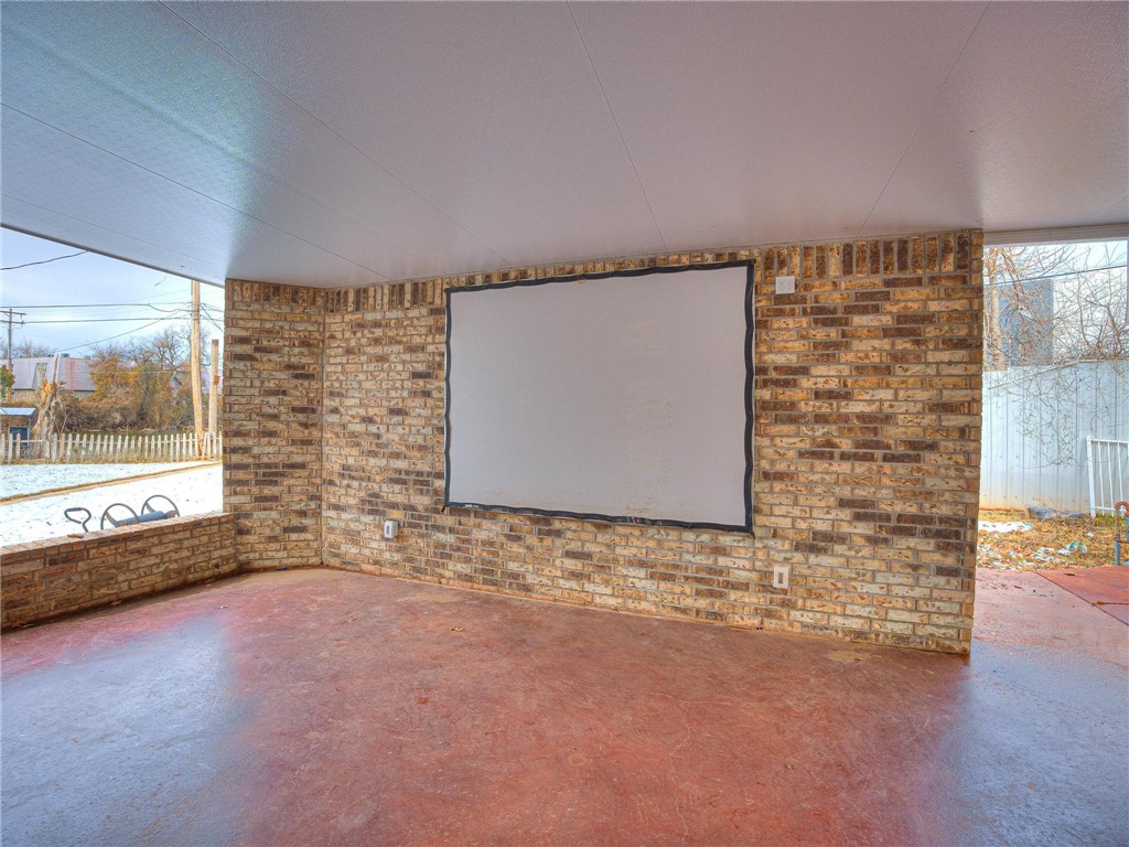 7336 N Hammond Circle, Warr Acres, OK 73132 home theater with brick wall and concrete floors