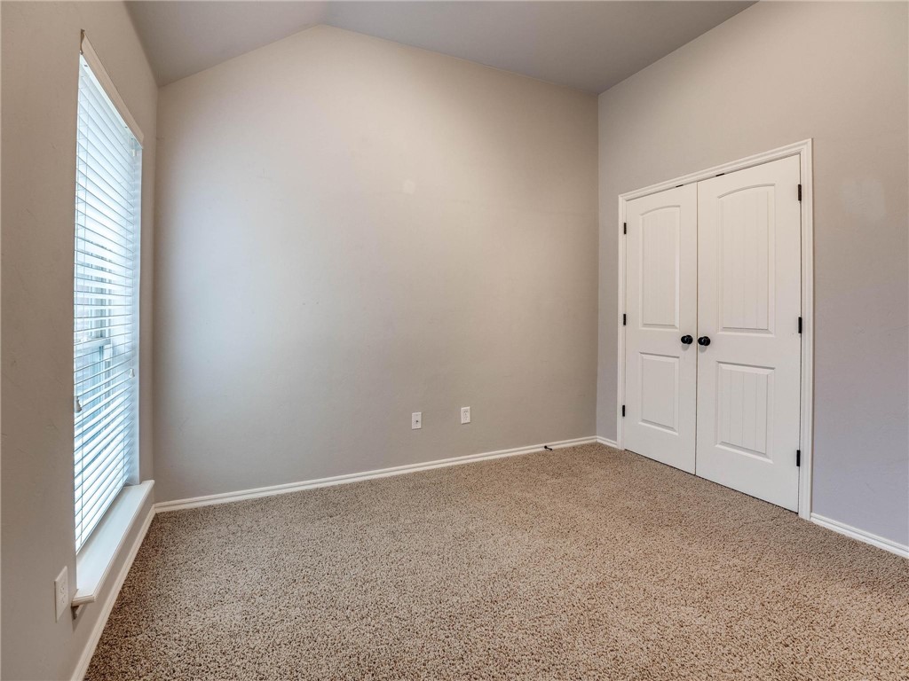 4311 Kensal Rise Place, Norman, OK 73072 carpeted spare room featuring vaulted ceiling