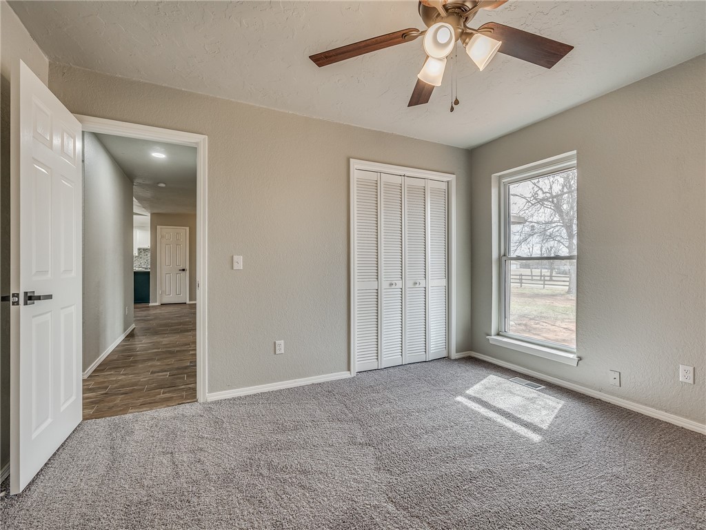 2233 W KEENS Drive, Mustang, OK 73064 unfurnished bedroom with ceiling fan, carpet flooring, and a closet