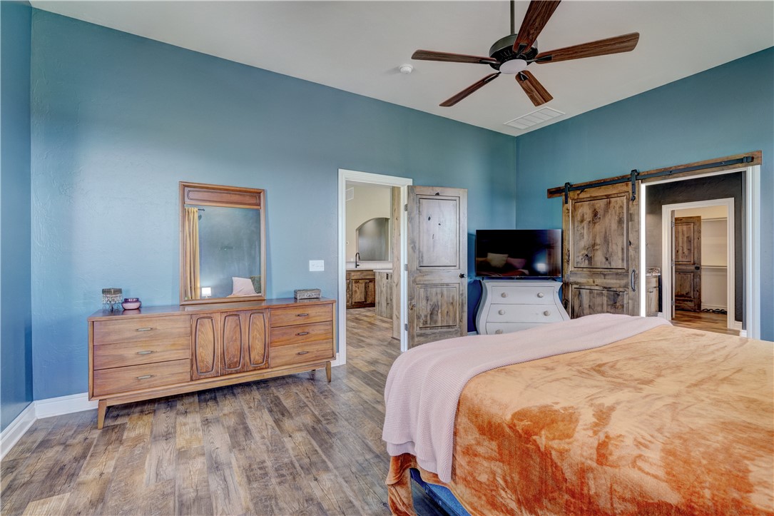 48294 Garretts Lake Road, Shawnee, OK 74804 hardwood floored bedroom with a ceiling fan and TV