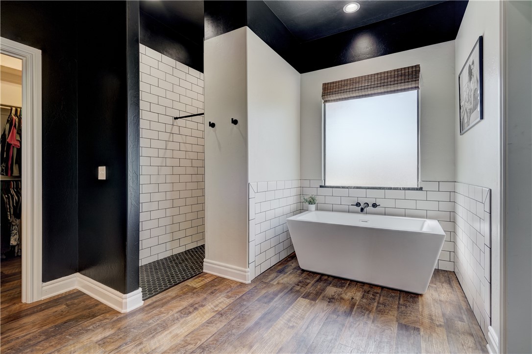 48294 Garretts Lake Road, Shawnee, OK 74804 bathroom featuring hardwood floors and shower with separate bathtub