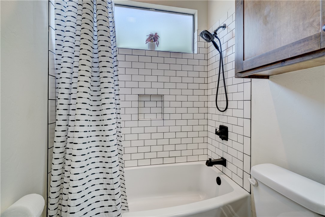 48294 Garretts Lake Road, Shawnee, OK 74804 bathroom featuring shower curtain, toilet, and bathtub / shower combination