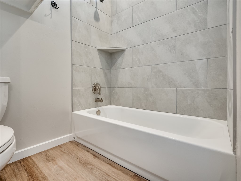 1005 Heritage Hills Drive, Tuttle, OK 73089 bathroom featuring hardwood flooring, toilet, and washtub / shower combination