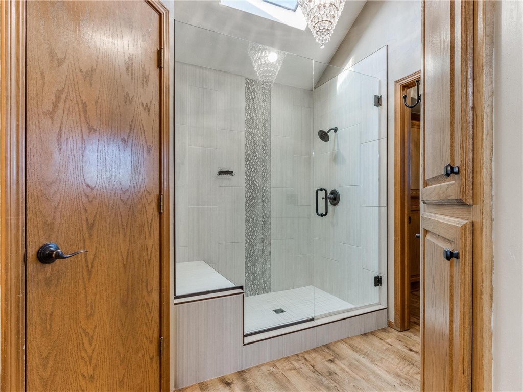 8124 N Mckee Boulevard, Oklahoma City, OK 73132 bathroom with hardwood floors, skylight, and shower with glass door