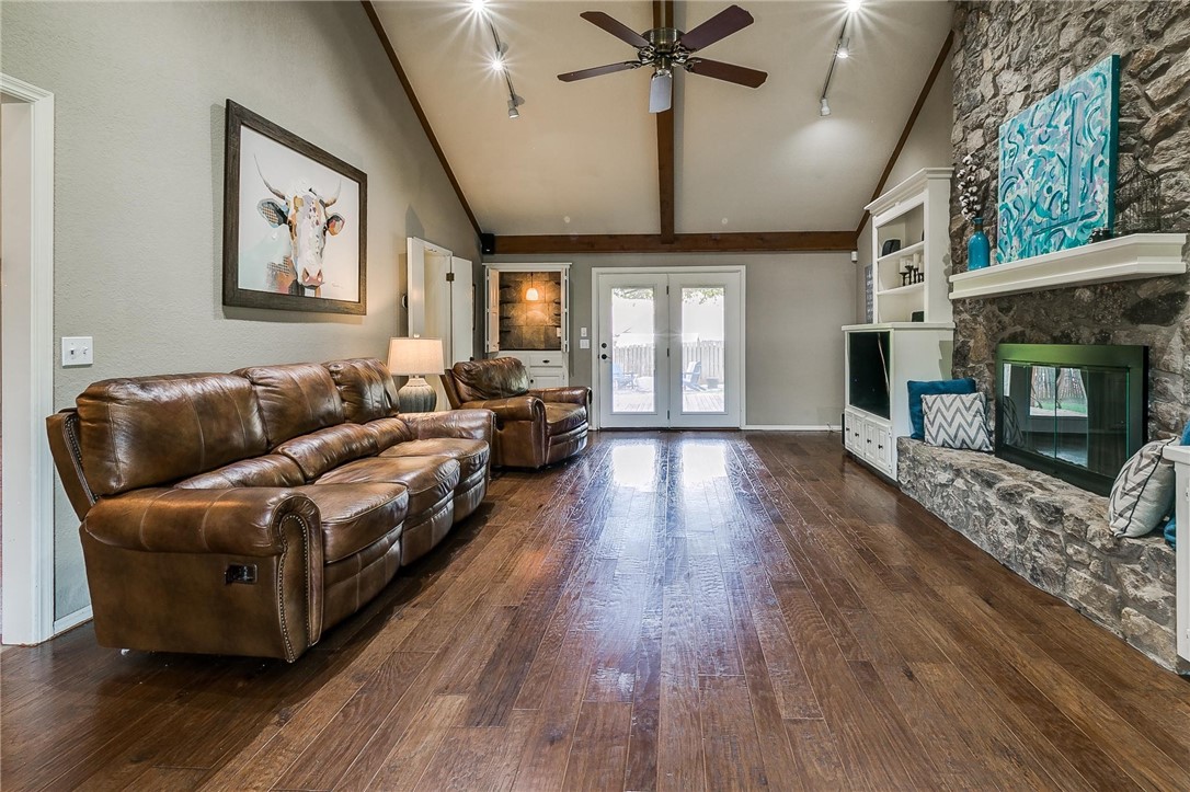 3815 Marked Tree Drive, Edmond, OK 73013 hardwood floored living room with a fireplace, french doors, lofted ceiling, natural light, and a ceiling fan