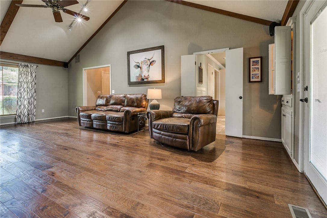 3815 Marked Tree Drive, Edmond, OK 73013 hardwood floored living room with lofted ceiling with beams, a ceiling fan, and natural light