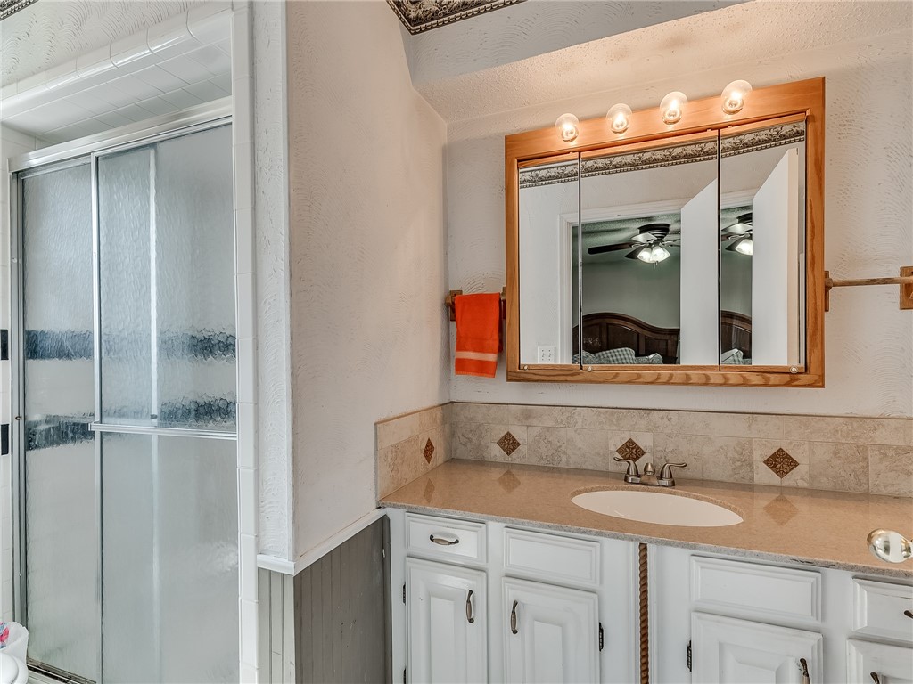 8909 Kenny Circle, Oklahoma City, OK 73132 bathroom featuring a ceiling fan, mirror, shower with shower door, and vanity