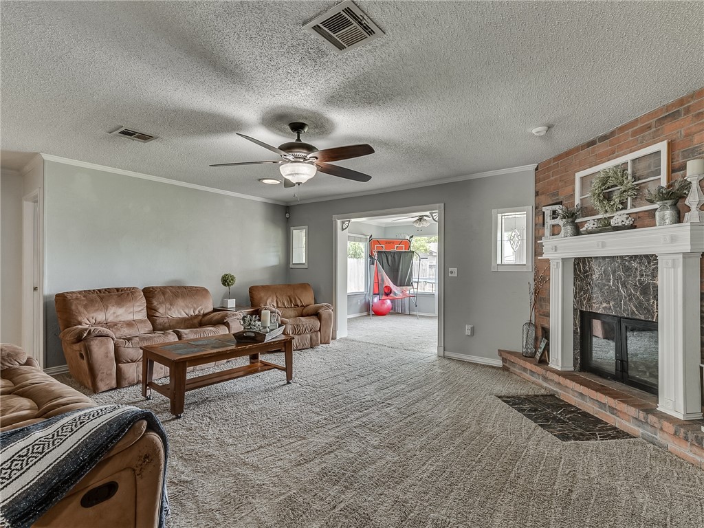 8909 Kenny Circle, Oklahoma City, OK 73132 carpeted living room with a ceiling fan, a fireplace, and natural light