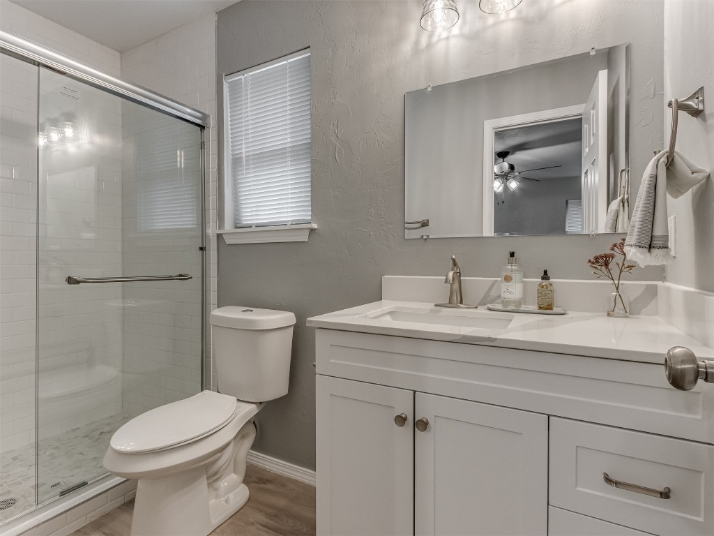 608 SW 26th Street, El Reno, OK 73036 full bathroom with a ceiling fan, vanity, shower with shower door, mirror, and toilet