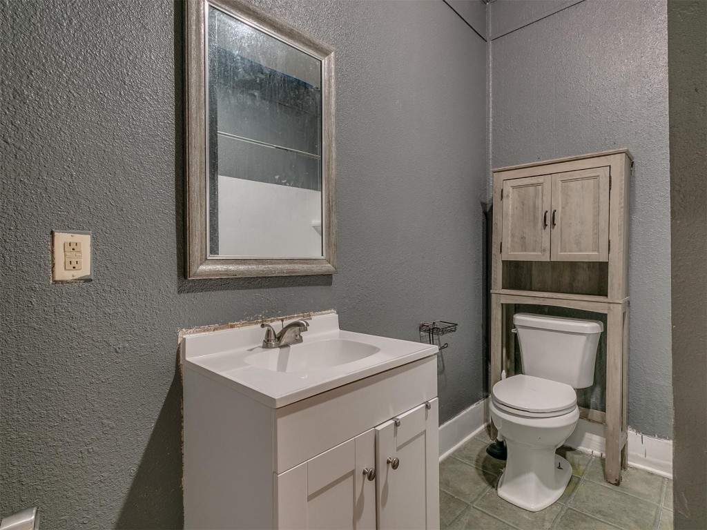 717 N Market Avenue, Shawnee, OK 74801 half bathroom with tile floors, toilet, mirror, and oversized vanity