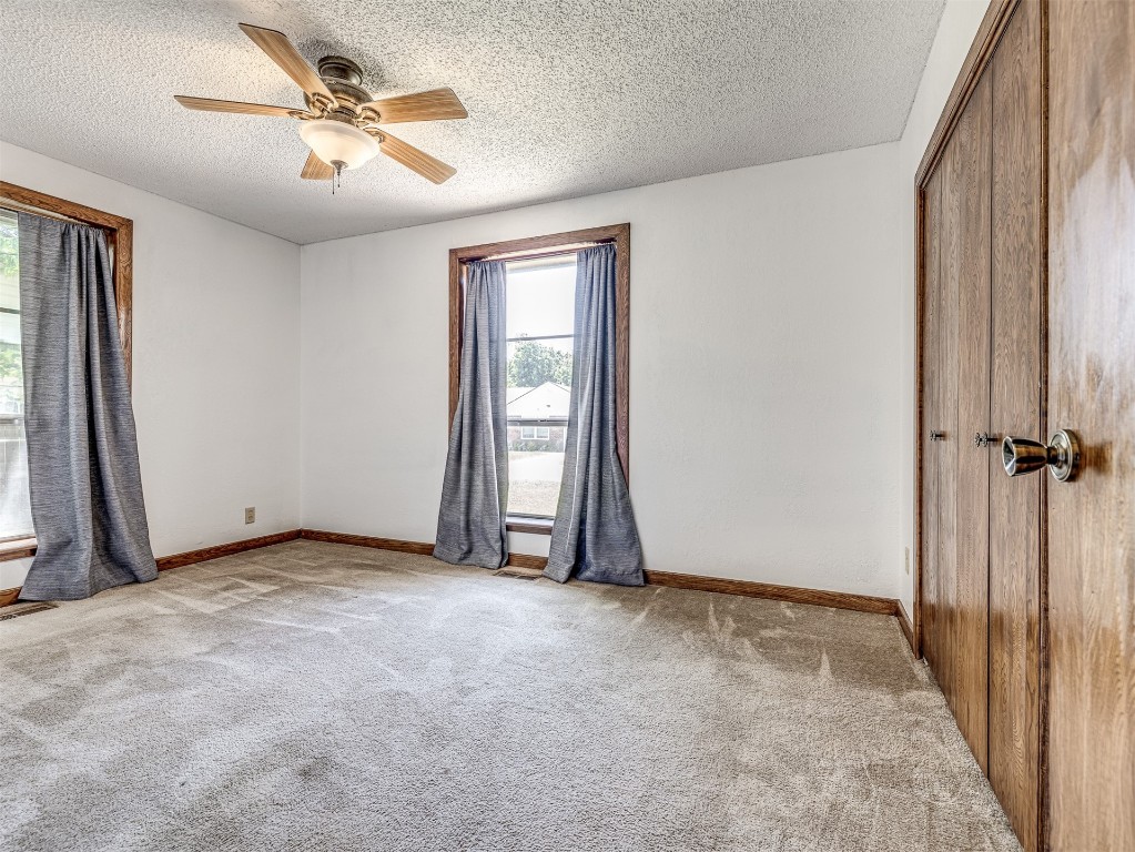 3305 NW 41st Street, Oklahoma City, OK 73112 empty room with light carpet, ceiling fan, and a textured ceiling