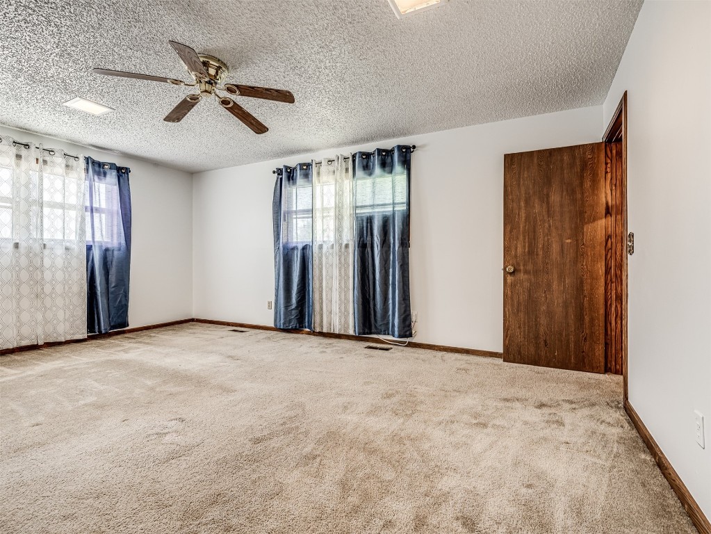 3305 NW 41st Street, Oklahoma City, OK 73112 spare room featuring a healthy amount of sunlight, light carpet, ceiling fan, and a textured ceiling
