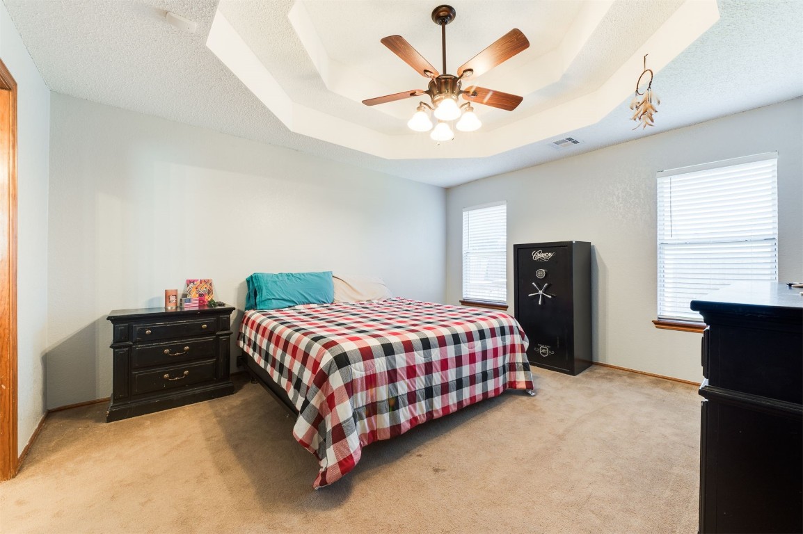 9306 Buttonfield Avenue, Moore, OK 73160 carpeted bedroom featuring ceiling fan, multiple windows, and a raised ceiling