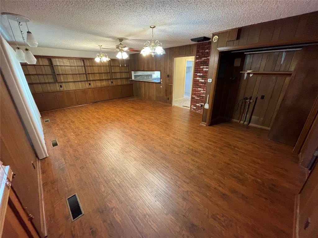 1815 Park Avenue, Chickasha, OK 73067-4505 interior space with a textured ceiling, brick wall, light hardwood floors, ceiling fan, and wooden walls