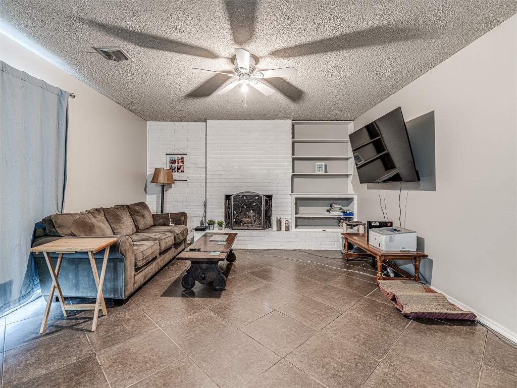 7516 NW 24th Street, Bethany, OK 73008 tiled living room featuring a textured ceiling, brick wall, and ceiling fan