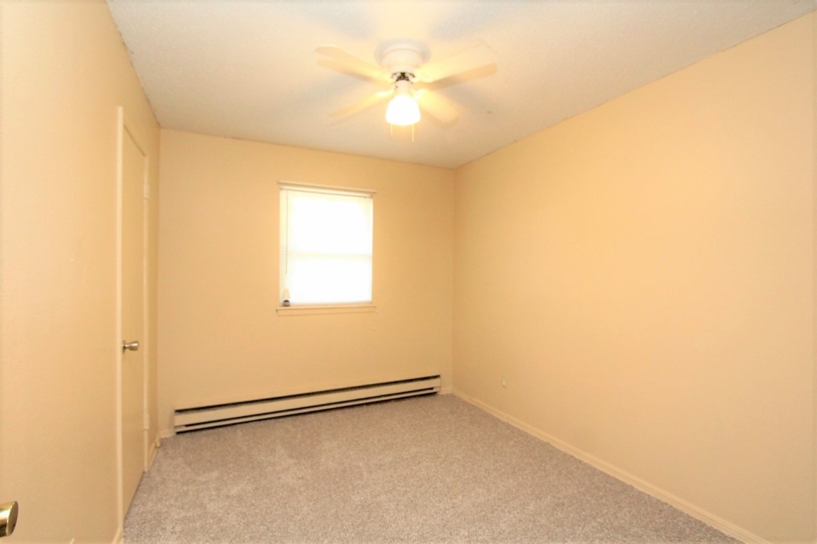 301 E Forest Lane, Mustang, OK 73064 carpeted spare room with a baseboard radiator and ceiling fan