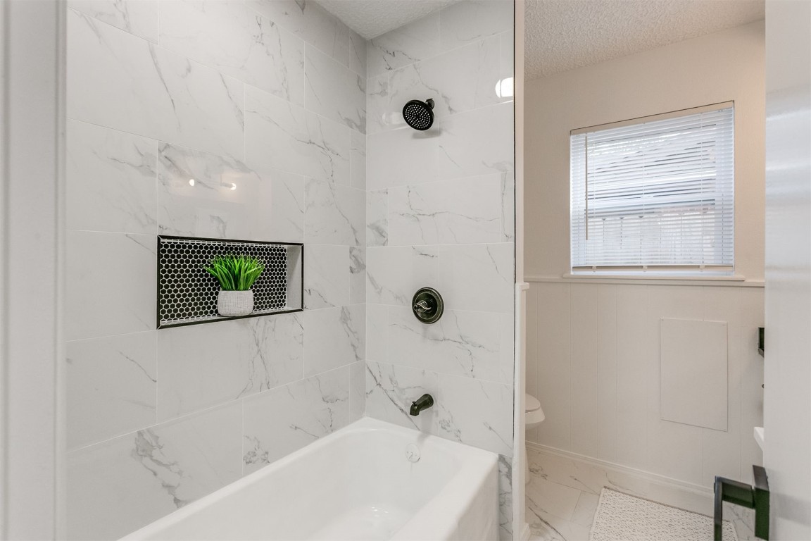 2600 SW 65th Street, Oklahoma City, OK 73159 bathroom featuring tiled shower / bath combo, light tile flooring, and a textured ceiling