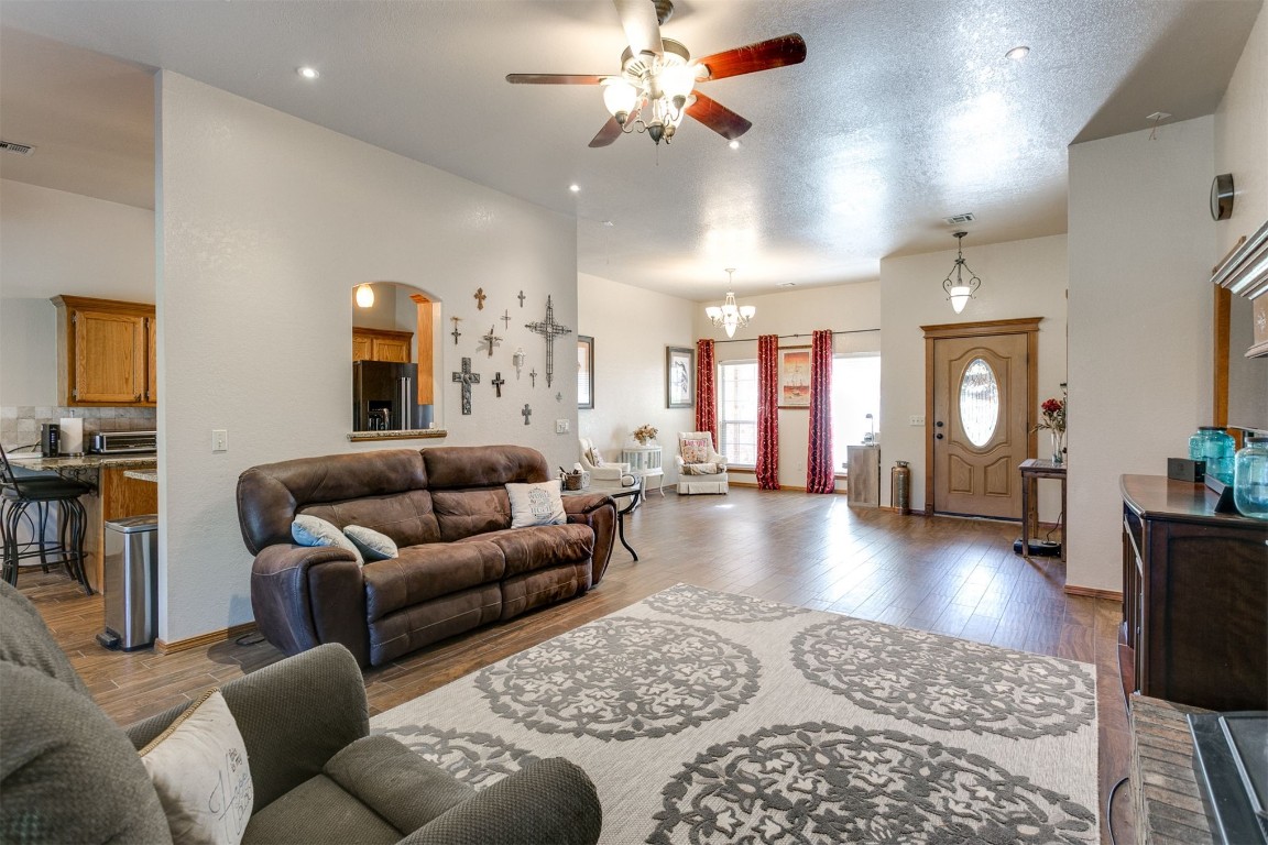 3324 Oakbriar Drive, Choctaw, OK 73020 hardwood floored living room featuring a textured ceiling and ceiling fan with notable chandelier