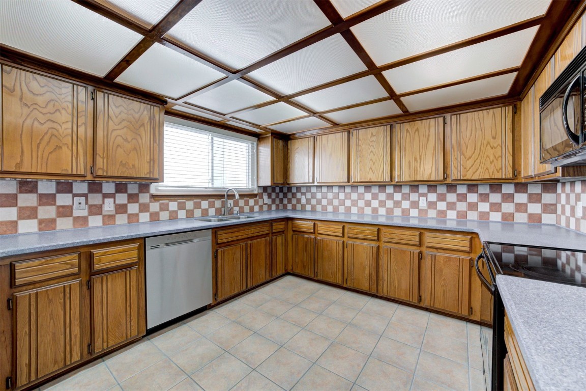 633 Westridge Court, Yukon, OK 73099 kitchen featuring coffered ceiling, sink, black appliances, light tile floors, and backsplash