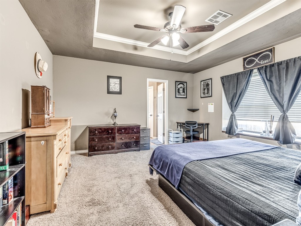 4205 Red Apple Terrace, Moore, OK 73160 bedroom with light carpet, a tray ceiling, and ceiling fan