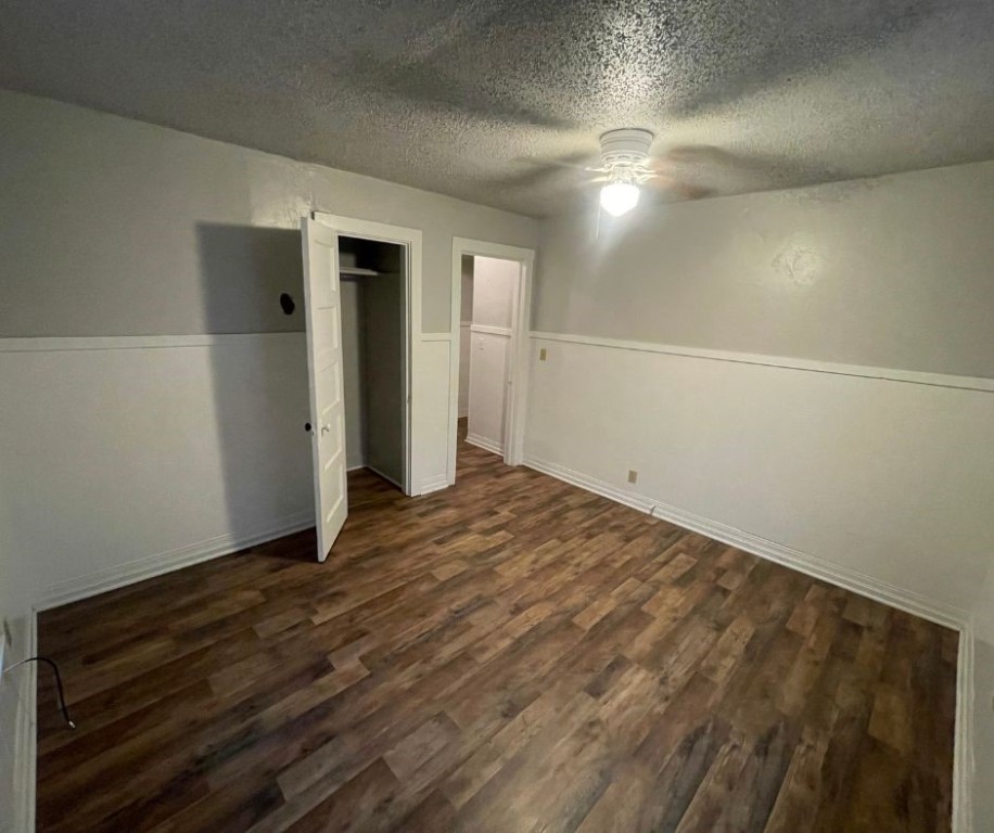 602 W Elm Street, El Reno, OK 73036 unfurnished bedroom featuring dark hardwood / wood-style floors, ceiling fan, a textured ceiling, and a closet