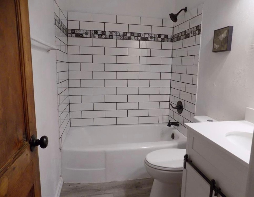 2402 Townsend Drive, El Reno, OK 73036 full bathroom with vanity, tiled shower / bath, toilet, and hardwood / wood-style flooring