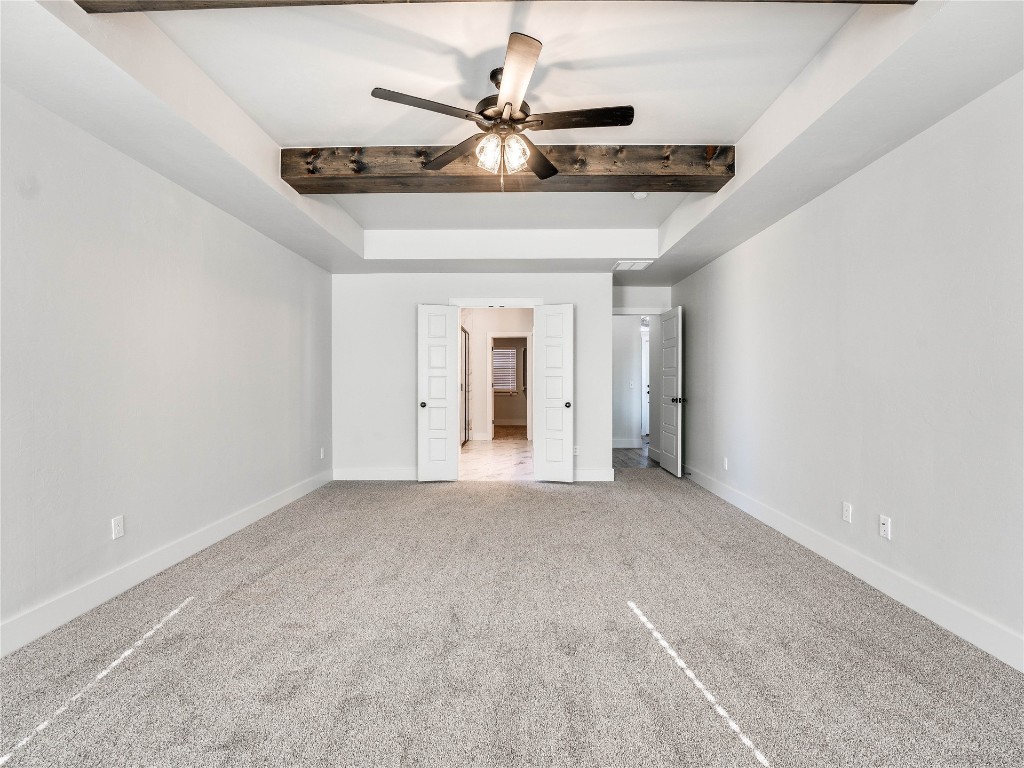 124 W Lynn Court Drive, Mustang, OK 73064 unfurnished bedroom featuring light carpet, ceiling fan, and beamed ceiling