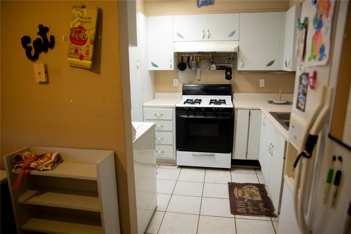 107 Cimarron Road, Burns Flat, OK 73647 kitchen featuring white cabinets, light tile flooring, and white gas range oven