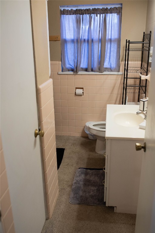 107 Cimarron Road, Burns Flat, OK 73647 bathroom featuring a healthy amount of sunlight, toilet, vanity, and tile walls