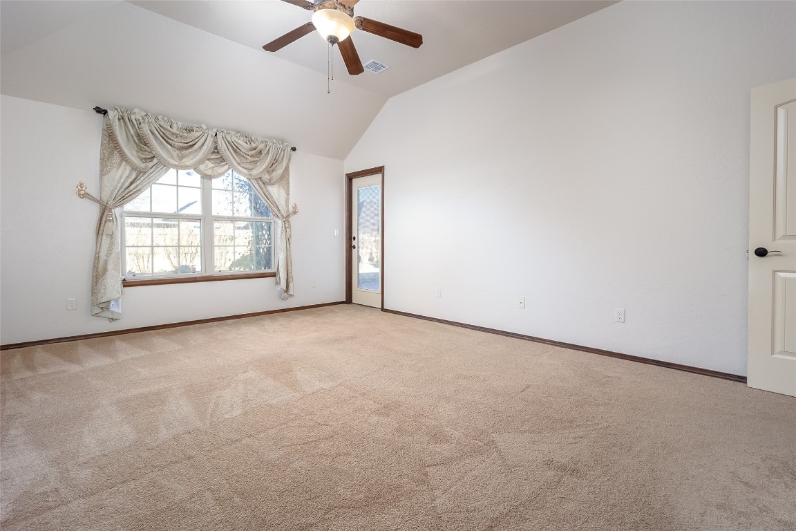 8509 NW 111th Street, Oklahoma City, OK 73162 empty room with light colored carpet, ceiling fan, and vaulted ceiling