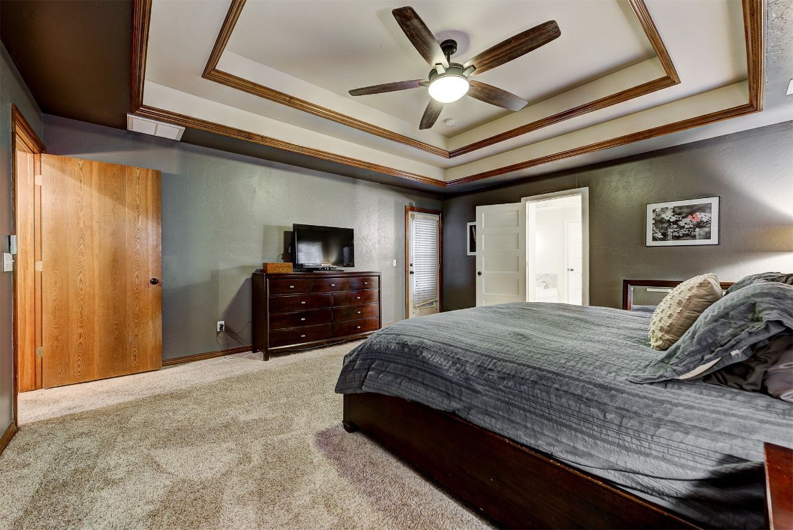 1304 Polly Way, Mustang, OK 73064 bedroom with light colored carpet, ceiling fan, and a raised ceiling