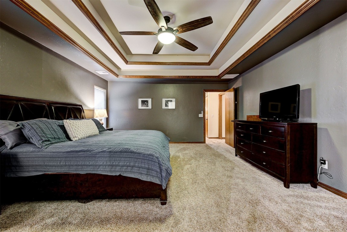 1304 Polly Way, Mustang, OK 73064 carpeted bedroom featuring ceiling fan, ornamental molding, and a raised ceiling