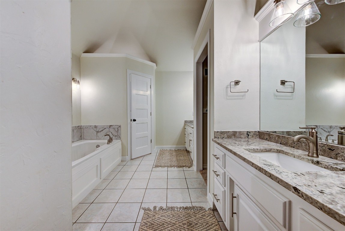 1304 Polly Way, Mustang, OK 73064 bathroom featuring ornamental molding, tile floors, a bath to relax in, and vanity with extensive cabinet space