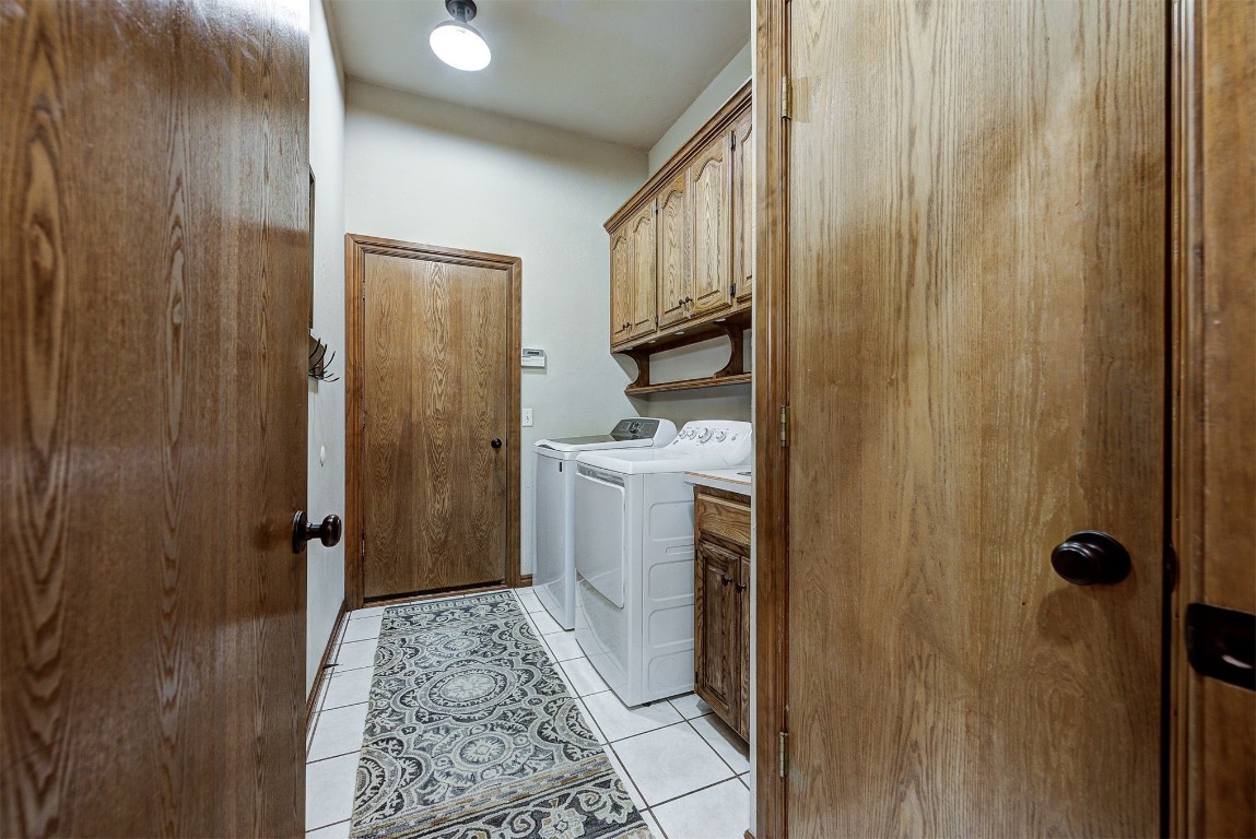 1304 Polly Way, Mustang, OK 73064 laundry area with light tile flooring, cabinets, and washer and clothes dryer