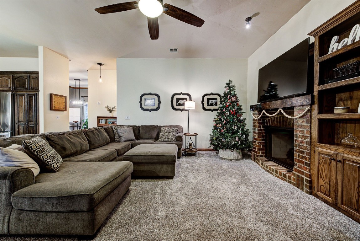 1304 Polly Way, Mustang, OK 73064 carpeted living room featuring ceiling fan and a fireplace